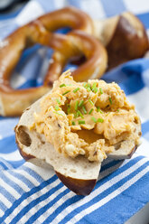 Laugenbrötchen mit Obatzda und Schnittlauch auf Serviette, Nahaufnahme - CSF018515