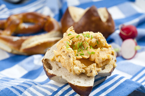 Laugenbrötchen mit Obatzda und Schnittlauch auf Serviette, Nahaufnahme - CSF018516