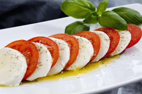 Mozzarellascheiben, Tomaten und Basilikum auf dem Schneidebrett, Nahaufnahme, lizenzfreies Stockfoto