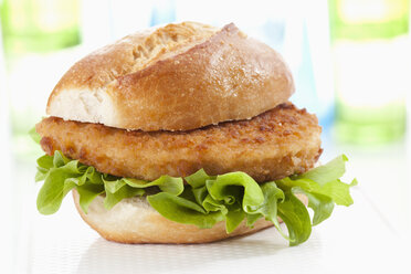 Bread roll with schnitzel on chopping board, close up - CSF018645