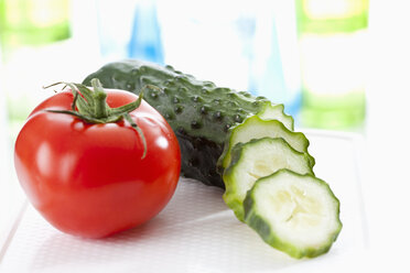 Cucumber and tomato on chopping board, close up - CSF018650
