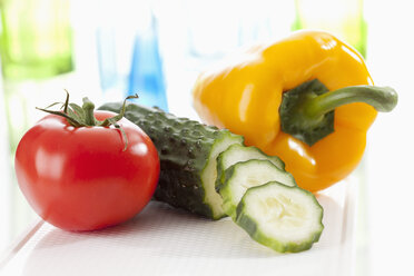 Cucumber, tomato and yellow bell pepper on chopping board, close up - CSF018651