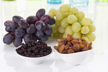 Bowls of currants and sultanas with grapes on white background, close up - CSF018613