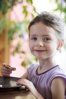 Germany, Bavaria, Girl eating toast with chocolate cream, portrait - SARF000002