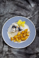 Rollmop herring with roasted potatoes and onions on a plate - CSF018788