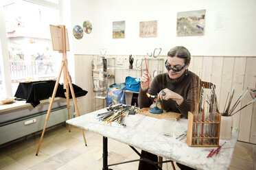 Germany, Bavaria, Mature woman making glass beads - RNF001196