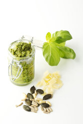 Basil Pesto in jar with seeds on white background, close up - MAEF006468