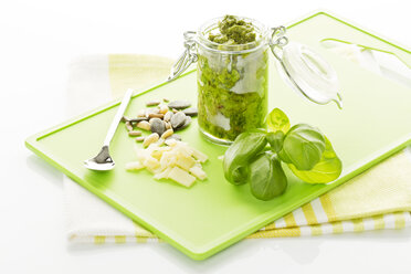 Basil Pesto in jar with seeds on chopping board, close up - MAEF006467