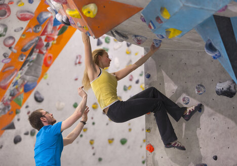 Germany, Bavaria, Munich, Young man helping woman to climb - HSIYF000218