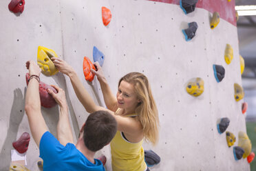 Germany, Bavaria, Munich, Young man helping woman to climb - HSIYF000188