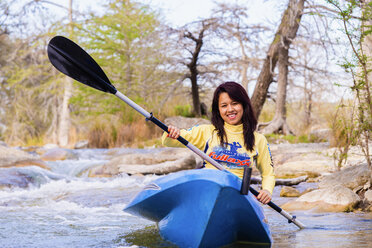 USA, Texas, Junge Frau beim Kajakfahren auf dem Frio River, lächelnd - ABAF000812