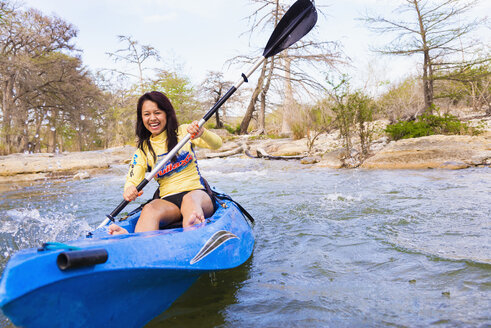 USA, Texas, Junge Frau beim Kajakfahren auf dem Frio River, lächelnd - ABAF000811