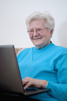 Deutschland, Berlin, Ältere Frau arbeitet am Laptop, lächelnd - BFRF000198