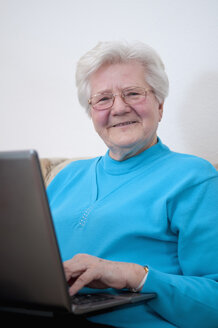 Deutschland, Berlin, Ältere Frau arbeitet am Laptop, lächelnd - BFRF000199