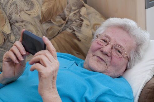 Deutschland, Berlin, Seniorin mit Smartphone, lächelnd - BFRF000208