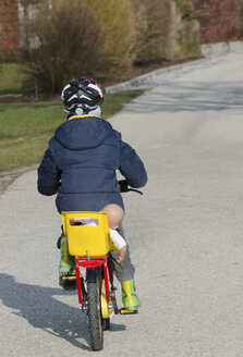 Austria, Boy cycling with doll on seat - CWF000032