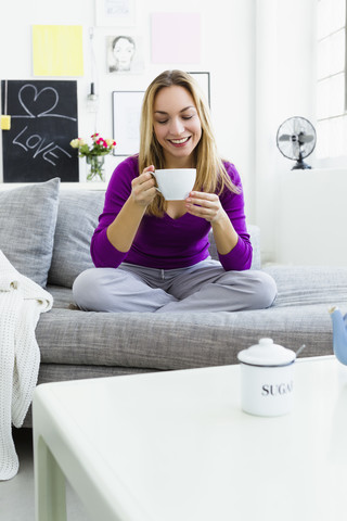 Deutschland, Bayern, München, Junge Frau hält Teetasse, lächelnd, lizenzfreies Stockfoto