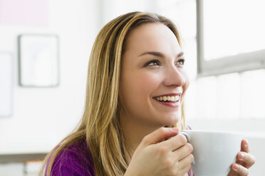 Deutschland, Bayern, München, Junge Frau hält Tasse Tee, lächelnd - SPOF000280