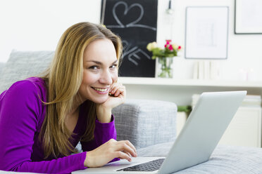 Germany, Bavaria, Munich, Portrait of young woman using laptop, smiling - SPOF000282