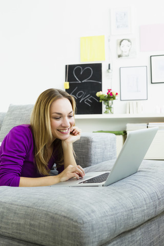 Germany, Bavaria, Munich, Young woman using laptop, smiling stock photo