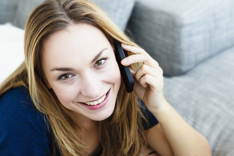 Deutschland, Bayern, München, Porträt einer jungen Frau, die mit einem Mobiltelefon spricht, Nahaufnahme, lizenzfreies Stockfoto