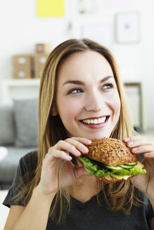 Deutschland, Bayern, München, Junge Frau hält Sandwich, schaut weg - SPOF000306