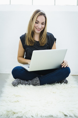 Germany, Bavaria, Munich, Young woman using laptop, smiling stock photo