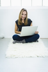 Germany, Bavaria, Munich, Portrait of young woman using laptop, smiling - SPOF000332