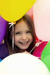 Porträt eines Mädchens inmitten von Luftballons, lächelnd - SARF000008