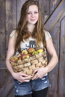 Deutschland, Porträt eines lächelnden Mädchens, das einen Korb mit Bio-Äpfeln hält - ONF000172