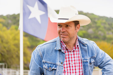 Texas, Älterer Mann vor Flagge mit Cowboyhut stehend - ABAF000824