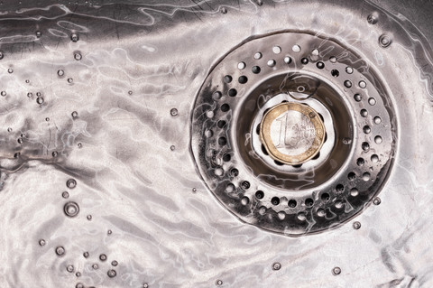 Euro coin in kitchen sink with flowing water, close up stock photo