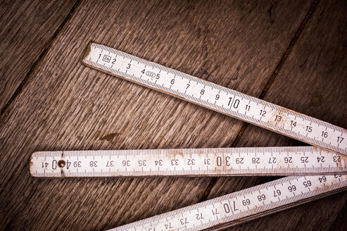 Old folding ruler on wooden background, close up - KJF000220