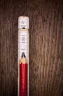 Old folding ruler with carpenter pencil on wooden background, close up - KJF000222