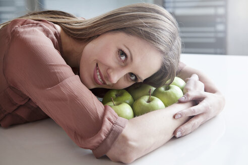 Deutschland, Nordrhein-Westfalen, Köln, Porträt einer Geschäftsfrau mit grünen Äpfeln, lächelnd - FMKF000731