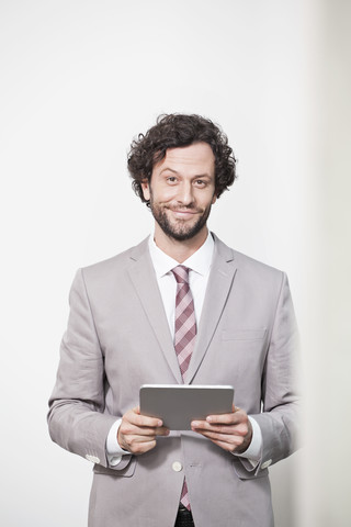 Deutschland, Nordrhein-Westfalen, Köln, Porträt eines Geschäftsmannes mit digitalem Tablet, lächelnd, lizenzfreies Stockfoto