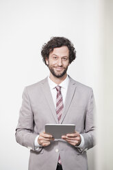 Deutschland, Nordrhein-Westfalen, Köln, Porträt eines Geschäftsmannes mit digitalem Tablet, lächelnd - FMKF000840
