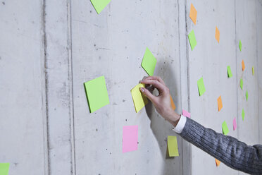 Germany, North Rhine Westphalia, Cologne, Businesswoman removing adhesive note - FMKF000786