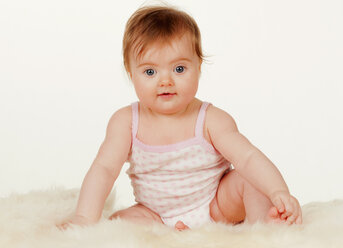 Portrait of baby girl sitting on carpet, close up - WWF002895