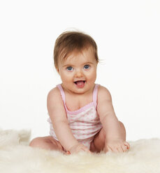 Portrait of baby girl sitting on bed, close up - WWF002900