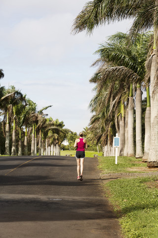 USA, Hawaii, Frau joggt auf der Straße, lizenzfreies Stockfoto