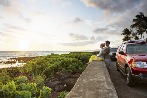 USA, Hawaii, Mittleres erwachsenes Paar beobachtet Sonnenuntergang am Strand - SKF001274