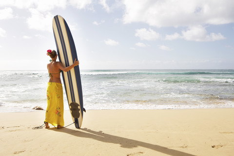 USA, Hawaii, Mittlere erwachsene Frau steht mit Surfbrett am Strand, lizenzfreies Stockfoto