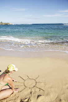 USA, Hawaii, Mittlere erwachsene Frau zeichnet Sonne auf Sand - SKF001294