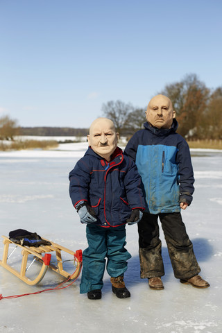 Germany, Boys with mask of old men in winter stock photo