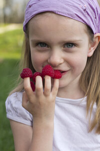 Deutschland, Bayern, Mädchen mit Himbeeren am Finger - SARF000019