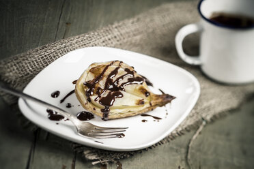 Pear puff pastry on plate with mug of chocolate sauce, close up - SBD000047