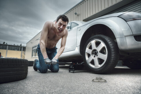 Germany, Bavaria, Kaufbeuren, Mature man changing car tire - DSC000065