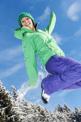 Österreich, Salzburg, Porträt einer jungen Frau, die in den Schnee springt, lächelnd - HHF004560