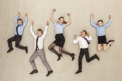 Germany, Berlin, Business kids flying against beige background - BAEF000583